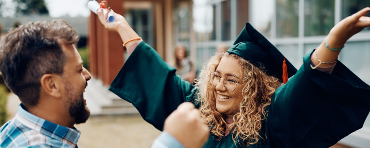 Happy graduate student celebrates graduation day with her father after receiving certificate at the university