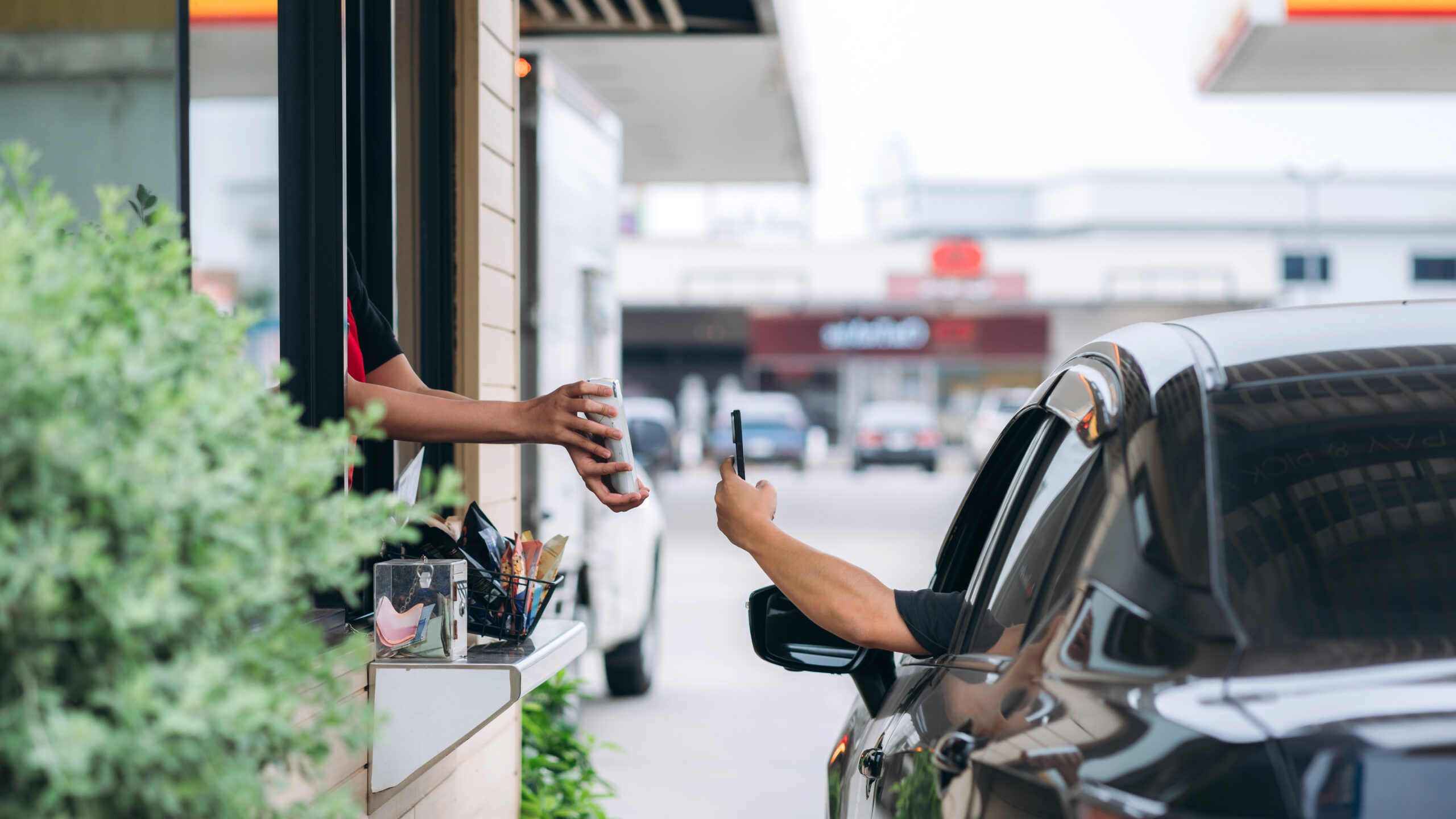 Young Man receiving coffee at drive thru counter.