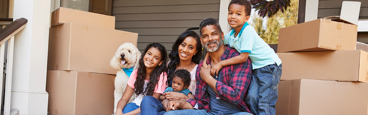 Family sitting on front porch surrounded by moving boxes.