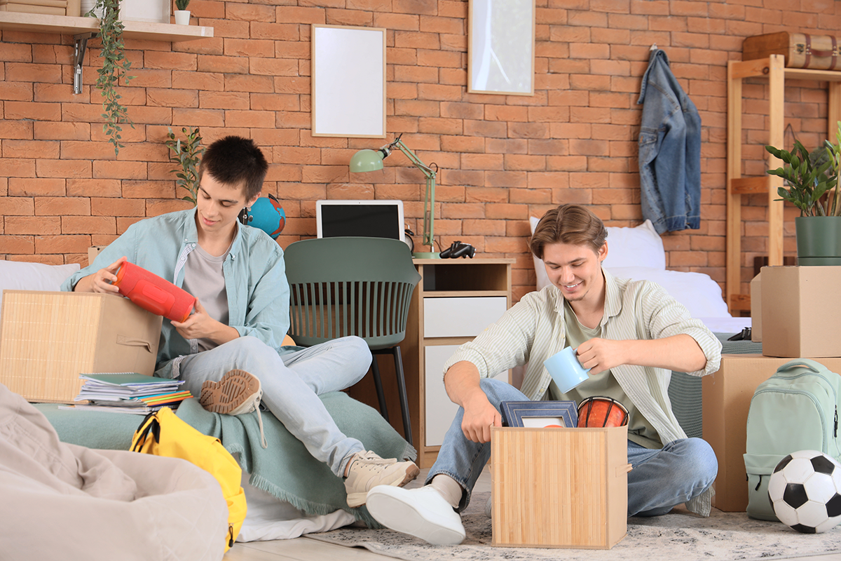 Male students unpacking things in dorm room on moving day
