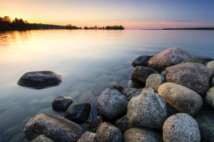 calm lake with boulders at sunset