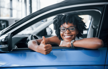 a woman in a new car flashes a thumbs-up